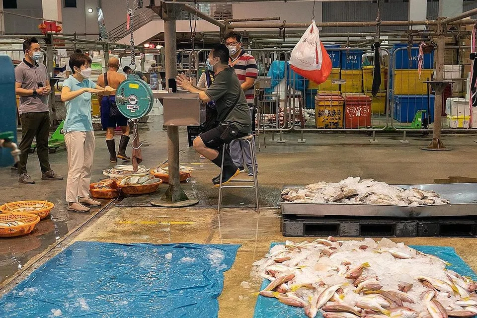 LANGKAH PERLINDUNGAN DIPERKUKUH: Cik Grace Fu (baju biru muda) berbual-bual dengan pekerja di Pelabuhan Perikanan Senoko semalam. Beliau berkata langkah keselamatan dipertingkat yang diambil di dua pelabuhan perikanan di Singapura adalah untuk melindungi pekerja, pedagang dan masyarakat lebih luas. - Foto SFA