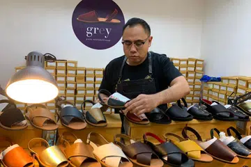 RINDU SUASANA NIAGA DI GEYLANG: Encik Trisno sedang menyusun sandal yang dijual di kedai baru yang disewa untuk jangka pendek di TKC. - Foto ihsan TRISNO ISHAK
