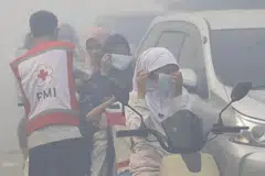 Penduduk memakai pelitup muka ketika asap tebal menyelubungi kawasan berhampiran Tapak Pelupusan Akhir (TPA) Jatiwaringin di Tangerang, wilayah Banten, pada 1 Julai 2026. Kebakaran yang memusnahkan kira-kira 15 hektar kawasan tapak pelupusan itu memaksa ratusan penduduk dipindahkan.