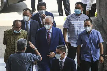 PERBICARAAN: Seorang penyokong (kiri) memberi salam kepada Datuk Seri Najib Razak (tengah) ketika dia tiba di kompleks Mahkamah Tinggi semalam dalam perbicaraan kes rasuah dan pengubahan wang haram membabitkan dana 1Malaysia Development Berhad (1MDB). Pendakwa raya mahu Riza Aziz dalam senarai pendakwaan - Foto EPA-EFE
