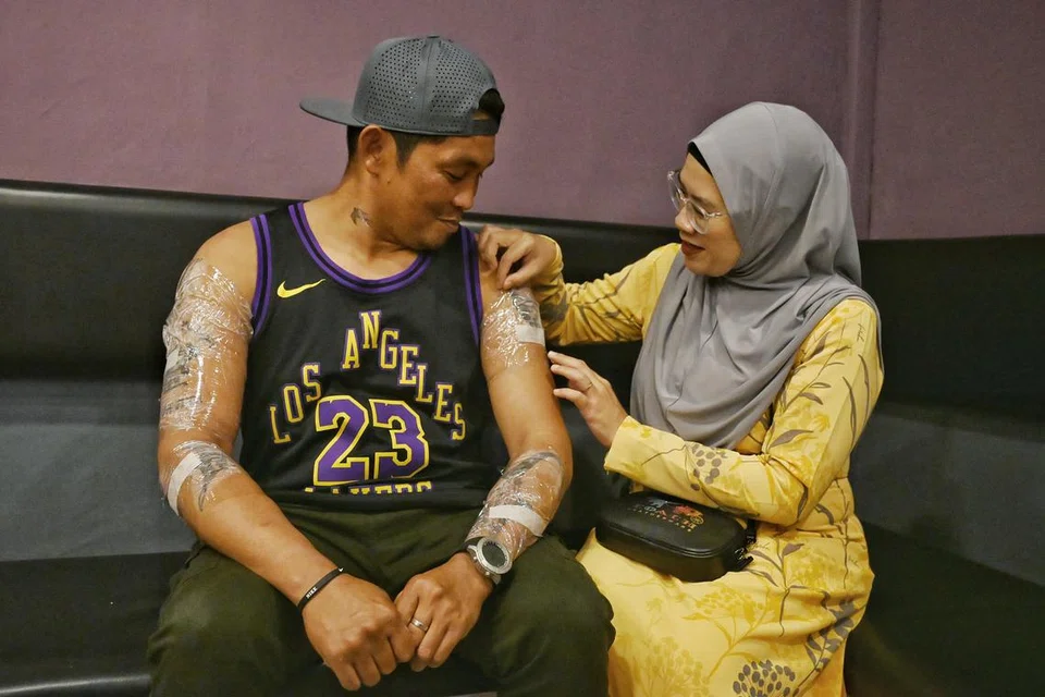 Cik Eriyana Subadi memeriksa krim kebas yang telah disapukan kepada tatu suaminya, Encik Jojo Sanchez Arriesgado, sementara menunggu sesi rawatan laser untuk menghapuskan tatu. 