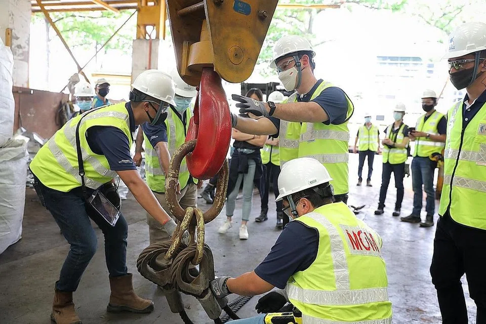 PERIKSA MESIN DEMI KESELAMATAN: Encik Zaqy (berdiri, kanan) menyertai pegawai MOM yang melakukan pemeriksaan keselamatan ke atas mesin di Esun International, sebuah syarikat dalam sektor perkilangan, semalam. - Foto BH oleh ONG WEE JIN