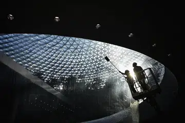 PEMBERSIHAN BAHAGIAN LUAR: Pekerja membersihkan bahagian luar ruangan yang diperbuat daripada akrilik yang merentangi lantai bawah tanah satu dan dua air terjun HSBC Rain Vortex di Jewel, Lapangan Terbang Changi. - Foto-foto BH oleh ARIFFIN JAMAR