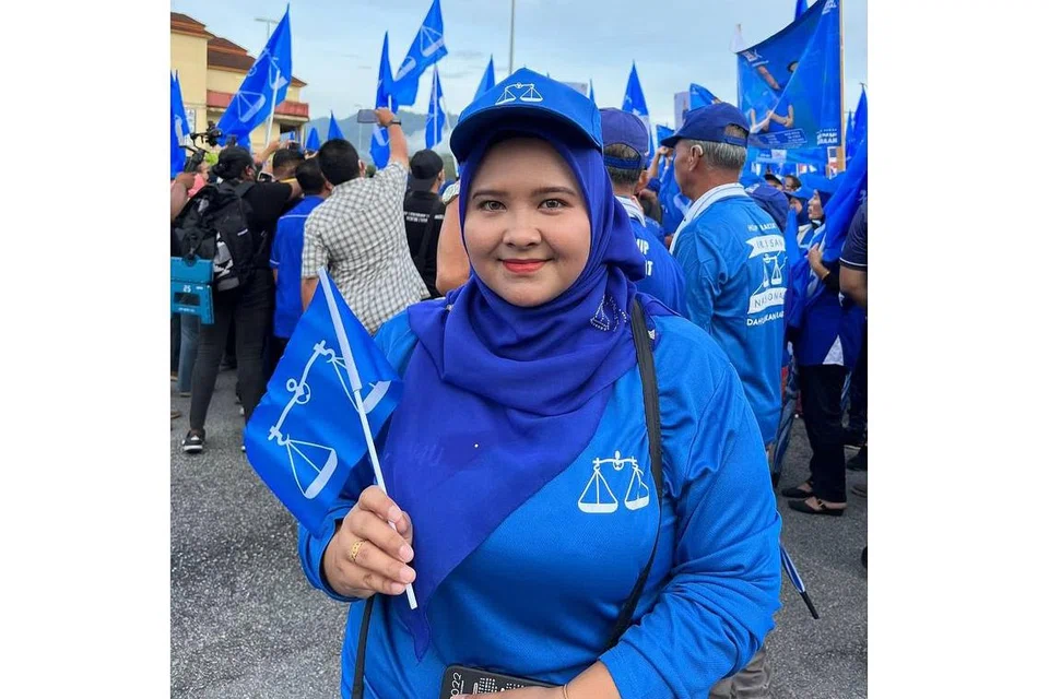 MERIAHKAN SUASANA: Seorang penduduk Perak, Cik Azna Zuliana Azizol Apizi, antara lain memakai topi dan kemeja-T dengan warna dan logo parti semasa berkempen dalam PRU15.