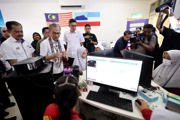 Menteri Komunikasi Datuk Fahmi Fadzil beramah mesra dengan murid-murid sempena pelancaran Nadi on Wheels (Now) peringkat Negeri Sabah sempena Hari Bersama Komuniti (HBK) di Pusat Sebaran Maklumat Nasional (NADI) Pekan Sindumin di sini pada 15 Oktober.