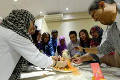 MENGHARAPKAN YANG TERBAIK: Encik Mikhail Goh (empat dari kanan) meluaskan amalan makan malam Tahun Baru Cina dan melambung 'lo hei' bersama kakitangan syarikatnya, Have Halal Will Travel, yang turut merangkumi pekerja Melayu. - Foto ZAINAL YAHYA
