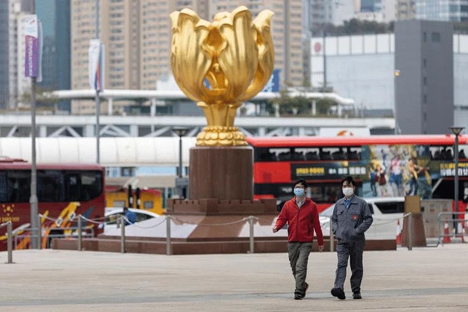 Dua lelaki memakai pelitup berdekatan tugu Golden Bauhinia di Hong Kong. - Foto EPA-EFE