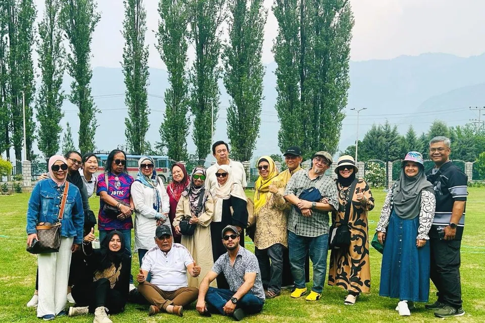 Cik Rafeeda Mohammad Hussein (duduk, berpakaian hitam) dan suami, Encik Manzoor Ahmad Wangnoo (duduk, kanan) bergambar dengan sekumpulan pelancong warga Singapura yang dibawa mereka dalam percutian di Kashmir. 