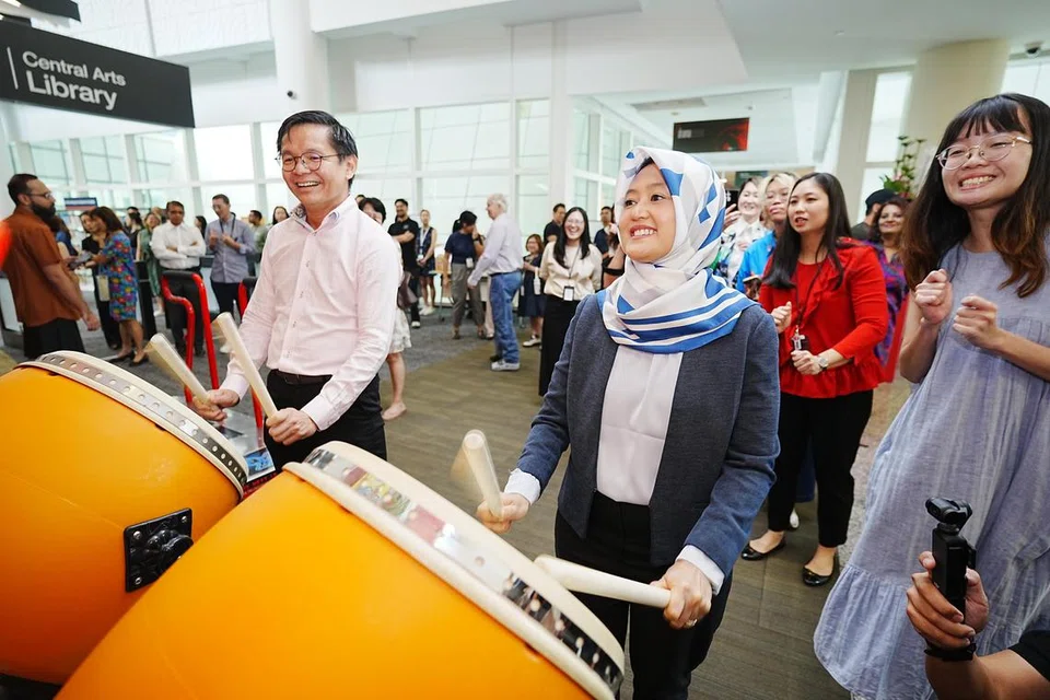 Menteri Negara (Penerangan dan Pembangunan Digital merangkap Kesihatan), Cik Rahayu Mahzam, dan Ketua Eksekutif NLB, Encik Ng Cher Pong, mencuba bermain gendang arked yang diletak di Perpustakaan Seni Sentral (CAL) di aras lima Perpustakaan Negara bagi kegiatan sempena perasmian perpustakaan itu.