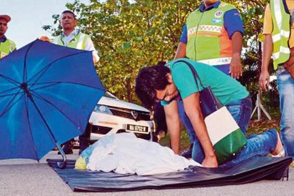 MATI DI TEMPAT KEJADIAN: Shamsul Azwan Abu Bakar menatap wajah anaknya yang terkulai selepas terbabit kemalangan di Kilometer 201.4, Lebuh raya PLUS, arah utara. - Foto HARIAN METRO