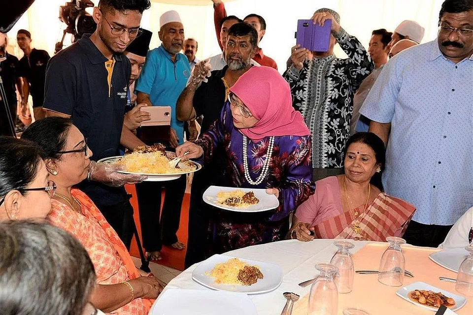 SAJIAN PRESIDEN: Seramai 20 tetamu khas dari Sree Narayana Mission dan Rumah Kanak-Kanak Jamiyah menikmati hidangan nasi beriani, yang disajikan sendiri oleh Presiden Halimah (tengah). Beliau melakukan demikian menerusi acara 'Beriani Amal Cabaran Presiden' di Masjid Khalid, Joo Chiat Road, kelmarin. - Foto MUIS