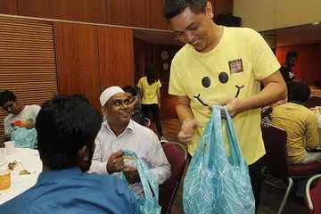 BERAMAH MESRA: Penolong Pengarah Operasi Royal Plaza on Scotts, Encik Azharie Mudakir, mengagihkan beg cenderahati kepada pekerja asing semasa majlis iftar di hotel tersebut Khamis lalu. - Foto ROYAL PLAZA ON SCOTTS