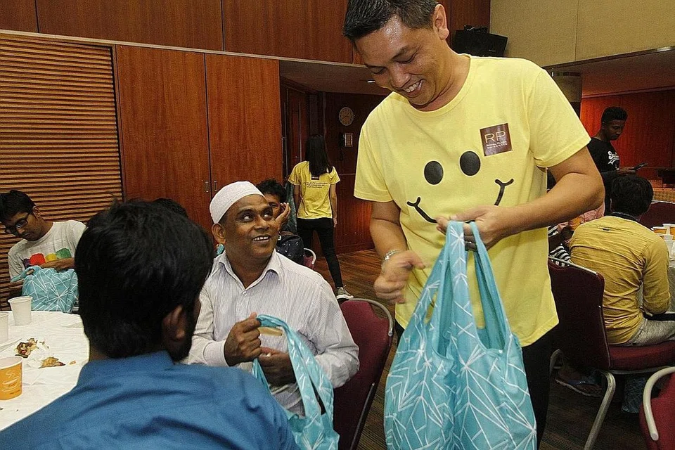 BERAMAH MESRA: Penolong Pengarah Operasi Royal Plaza on Scotts, Encik Azharie Mudakir, mengagihkan beg cenderahati kepada pekerja asing semasa majlis iftar di hotel tersebut Khamis lalu. - Foto ROYAL PLAZA ON SCOTTS