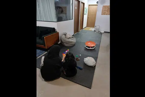 Cik Suhaila (kiri) dan anaknya duduk di atas tikar getah yang dipasang di ruang tamu bagi mengelakkan bunyi hentakan kaki daripada menjejas jiran di bawah.
