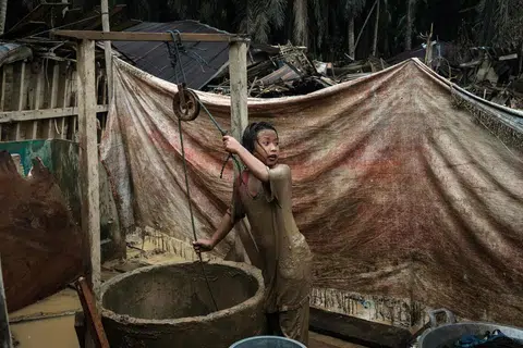 Baiti Arafah menimba air dari sebuah perigi untuk membersihkan diri selepas bermain di lopak berlumpur di Babo, Aceh Tamiang, Sumatera Utara, pada 15 Disember, susulan banjir kilat. 