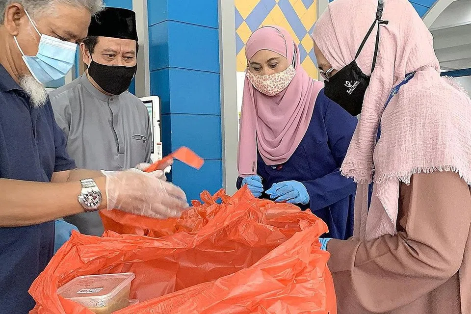 SINGSING LENGAN: Pengerusi eksekutif Masjid Al-Istighfar Encik Azman Ariffin (dua dari kiri) dan hos, Cik Hanim Mohd Saleh (dua dari kanan) bersama relawan menyediakan bungkusan bubur buat jemaah. - Foto BH oleh ERVINA MOHD 