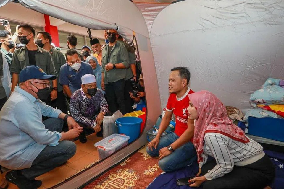 SANTUNI MANGSA: Perdana Menteri, Datuk Seri Anwar Ibrahim (kiri, bertopi), dan Menteri Besar Kelantan, Datuk Mohd Nassuruddin Daud (tiga dari kanan), menyantuni mangsa banjir yang berlindung di pusat pemindahan sementara Sekolah Menengah Kebangsaan Agama Lati, Pasir Mas, Kelantan pada 28 Disember.