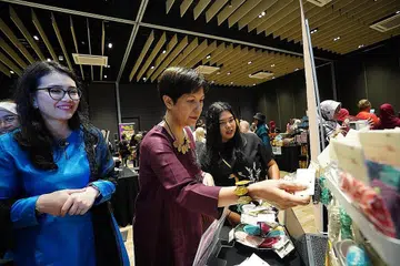 SOKONG PERNIAGAAN WANITA: Cik Indranee Rajah, (tengah) dan Cik Hazlina Abdul Halim,(kiri) melihat barangan yang dijual di salah sebuah gerai di pasar mini semasa acara IWD anjuran PPIS pada 12 Mac lalu. - Foto PPIS