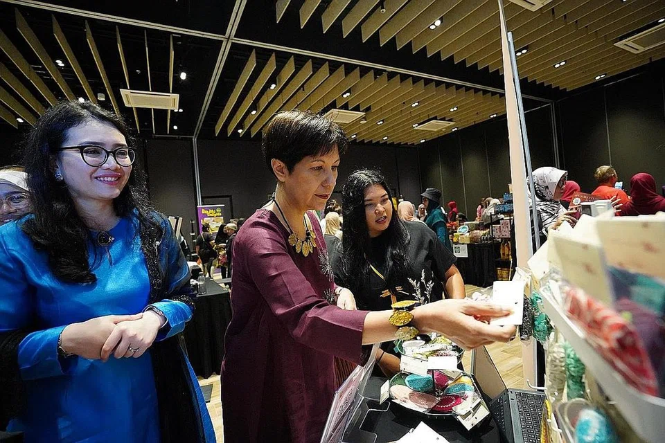 SOKONG PERNIAGAAN WANITA: Cik Indranee Rajah, (tengah) dan Cik Hazlina Abdul Halim,(kiri) melihat barangan yang dijual di salah sebuah gerai di pasar mini semasa acara IWD anjuran PPIS pada 12 Mac lalu. - Foto PPIS