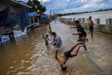 MAIN AIR: Sekumpulan kanak-kanak bermain di kawasan jalan raya yang banjir selepas hujan lebat berdekatan masjid Tha-it di wilayah Nonthaburi di luar Bangkok, Thailand, kelmarin.