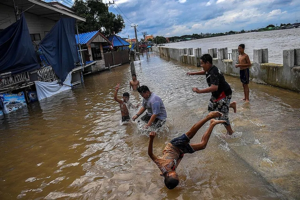 MAIN AIR: Sekumpulan kanak-kanak bermain di kawasan jalan raya yang banjir selepas hujan lebat berdekatan masjid Tha-it di wilayah Nonthaburi di luar Bangkok, Thailand, kelmarin.