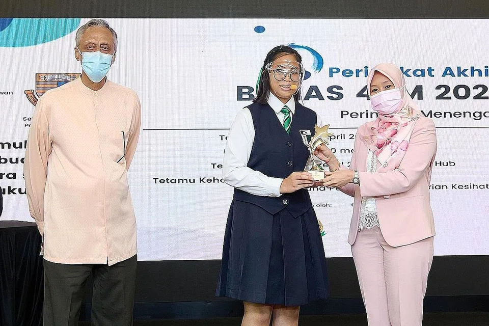 PEMBAHAS TERBAIK: Tetamu Terhormat, Setiausaha Parlimen (Kesihatan), Cik Rahayu Mahzam (kanan) menyampaikan hadiah kepada pelajar Tahun 4 dari Sekolah Perempuan Raffles, Iman Nabilah Yasmeen Yunus, yang terpilih sebagai Pembahas Terbaik keseluruhan dalam pertandingan bahas anjuran 4PM baru-baru ini. Di kiri ialah Presiden 4PM, Encik Izzudin Taherally. - Foto 4PM