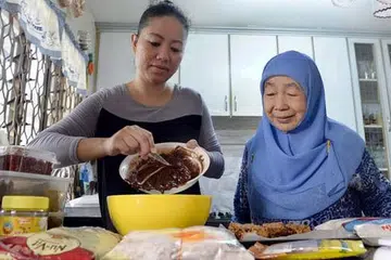 MENDAPAT SOKONGAN NENEK: Cik Fatimah dibantu Puan Noor Aishah membuat makanan jualan di rumah neneknya dalam kawasan East Coast Road baru-baru ini. - Foto TAUFIK A. KADER