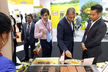 MELAYAN PENIAGA ANTARABANGSA: Encik Azhar (kanan) melayan peniaga Arab di gerainya ketika menyertai GulFood di Dubai. - Foto ihsan AZHAR SULAIMAN