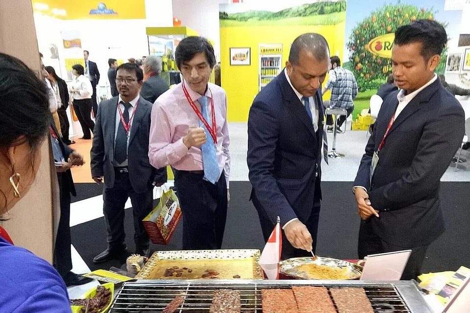 MELAYAN PENIAGA ANTARABANGSA: Encik Azhar (kanan) melayan peniaga Arab di gerainya ketika menyertai GulFood di Dubai. - Foto ihsan AZHAR SULAIMAN