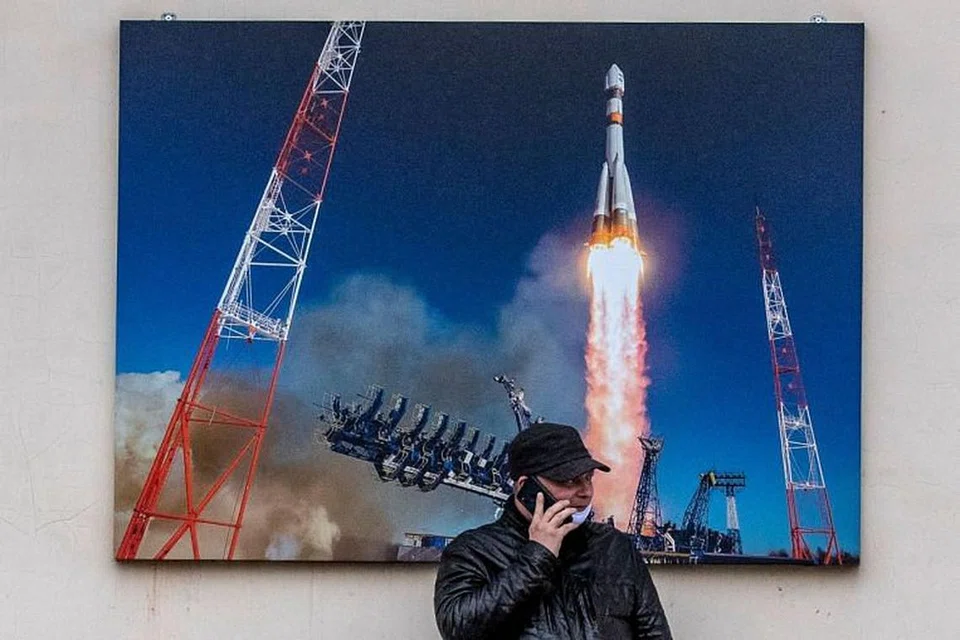 Seorang lelaki bercakap di telefonnya di depan gambar kapal angkasa Russia Soyuz berlepas, di tengah Moscow pada 2 Jun 2020. 
