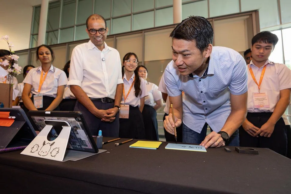 Pemangku Menteri Kebudayaan, Masyarakat dan Belia, Encik David Neo (kanan), menulis ‘keharmonian kaum’ dalam bahasa Korea di reruai yang disediakan sekumpulan pelajar Maktab Rendah Jurong Pioneer di di Persidangan HarmonyWorks! pada 12 Julai. Bersama beliau ialah Menteri Negara Kanan (Pendidikan merangkap Kemampanan dan Sekitaran), Dr Janil Puthucheary.