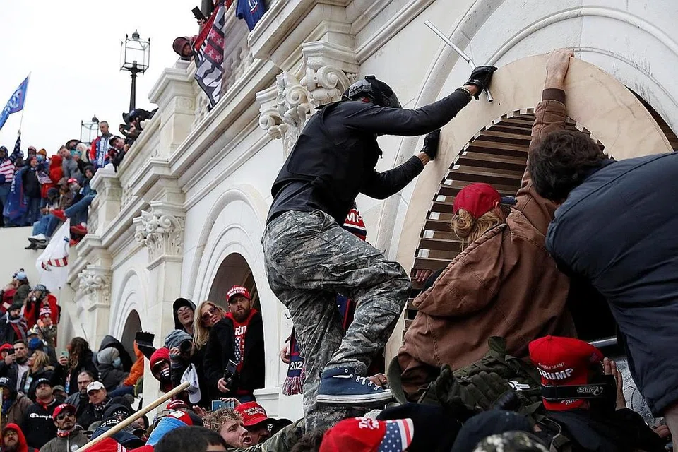 SERANG BANGUNAN CAPITOL: Penunjuk perasaan pro-Trump kelihatan memanjat tembok apabila mereka menceroboh bangunan Capitol di ibu kota Amerika dalam usaha mereka mencegah Kongres mengiktiraf kemenangan Encik Joe Biden dalam pilihan raya presiden. - Foto REUTERS