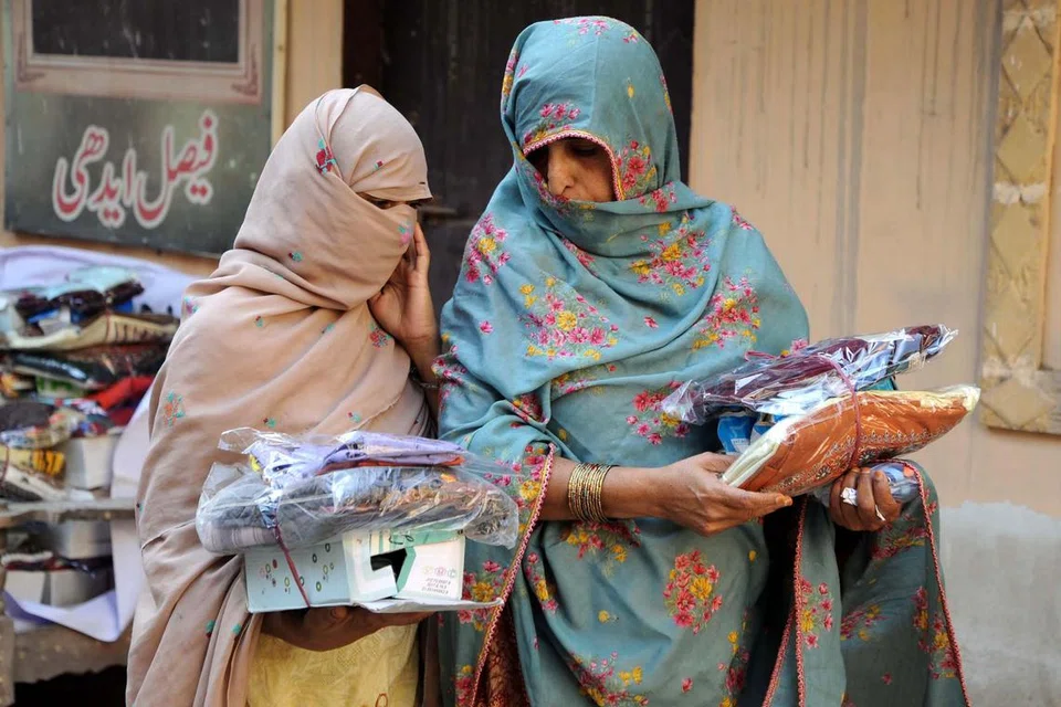 Dua wanita Pakistan menerima pakaian secara percuma yang diagihkan oleh Pertubuhan Kebajikan Edhi di bandar Hyderabad pada 29 Mac.