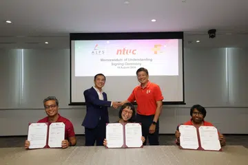 Setiausaha Agung Kongres Kesatuan Sekerja Kebangsaan (NTUC), Encik Ng Chee Meng (berdiri, berbaju merah) dan pengerusi agensi pemerolehan dan rantaian bekalan bersepadu bagi sektor penjagaan kesihatan awam Singapura, ALPS, Encik Ong Kim Pong (dua dari kiri), menyaksikan pemeteraian Memorandum Persefahaman (MOU) yang ditandatangani (dari kiri, baris depan) Setiausaha Eksekutif Kesatuan Pekerja Perkhidmatan Penjagaan Kesihatan (HSEU), Encik Steven Goh; Ketua Pegawai Eksekutif (CEO) ALPS, Cik Yong Hwee Yee; dan Presiden NTUC dan HSEU, Cik K Thanaletchimi, pada 19 Ogos.