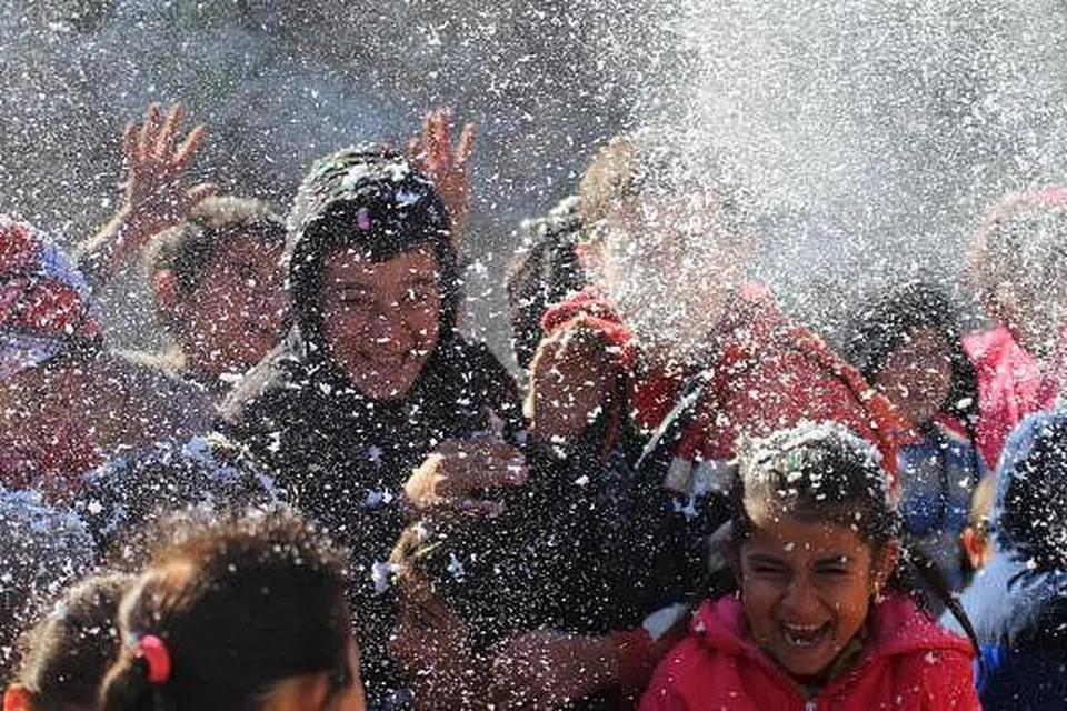 CERIA DALAM DUKA: Kanak-kanak yang tiada tempat tinggal bermain dengan buih yang disemburkan oleh sukarelawan yang menghiburkan mereka di khemah-khemah sementara di wilayah Latakia, dekat sempadan Syria-Turkey pada 4 Disember lalu. - Foto REUTERS.