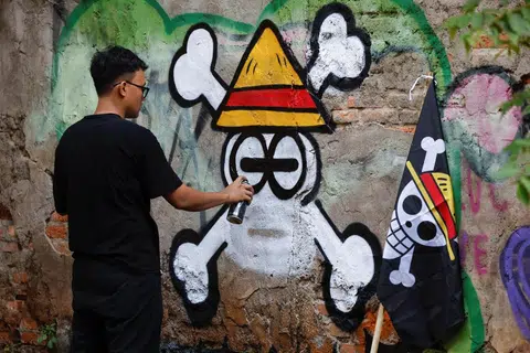 Kemas Muhammad Firdaus, 28 tahun, melukis mural yang menggambarkan lambang Jolly Roger daripada siri anime dan manga Jepun terkenal ‘One Piece’ di Bekasi, wilayah Jawa Barat, Indonesia, 7 Ogos 2025.