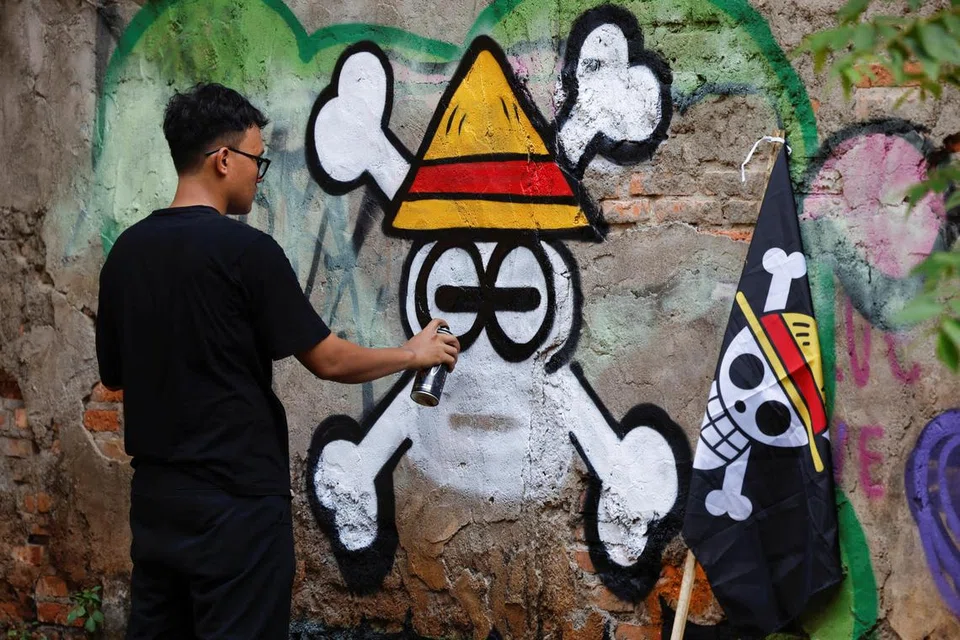 Kemas Muhammad Firdaus, 28 tahun, melukis mural yang menggambarkan lambang Jolly Roger daripada siri anime dan manga Jepun terkenal ‘One Piece’ di Bekasi, wilayah Jawa Barat, Indonesia, 7 Ogos 2025.