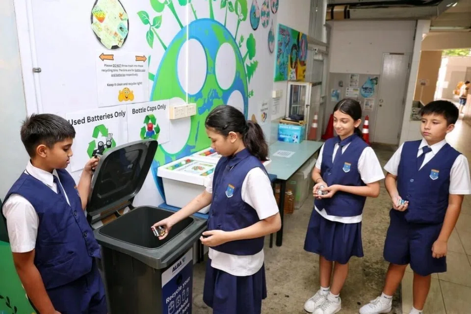 Duta Hijau dan pelajar Darjah 5, (dari kiri) Iyer Aurob, Basyeerah Muhammad Muzzammil, Aanya Uppal dan Oscar Booth, meletakkan bateri terpakai ke dalam tong pengumpulan di kantin Sekolah Rendah Bedok Green pada 8 Oktober.