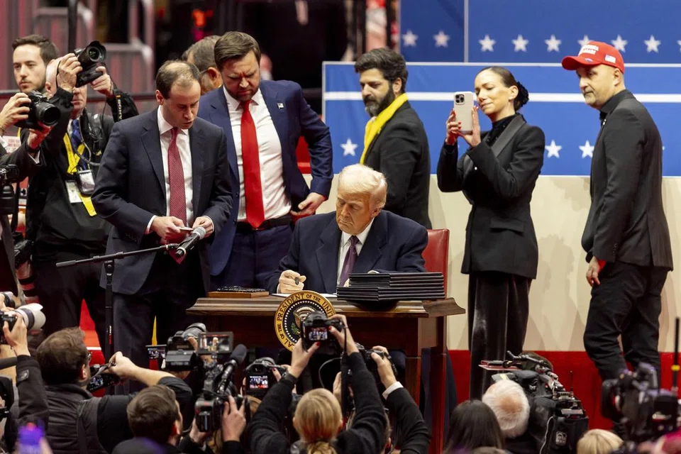 Presiden Amerika Syarikat, Donald Trump, menandatangani beberapa arahan eksekutif di atas pentas semasa acara pelantikan presiden di Capital One Arena, Washington, DC, pada 20 Januari 2025. 