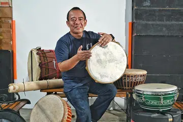 TURUNKAN KEMAHIRAN: Pengasas bersama dan pengarah eksekutif kumpulan genderang yang menggunakan alat muzik tradisional Melayu, Nadi Singapura, Encik Yaziz Hassan, meletakkan syarat pemain yang merosakkan rebana atau jidur perlu membaikinya sendiri supaya mereka tahu cara membaiki alat-alat muzik tradisional Melayu itu. 