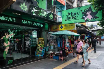 Orang ramai berjalan melepasi premis penjualan ganja Mary Jane di Bangkok pada 23 Mei 2025.