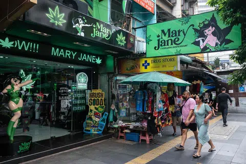 Orang ramai berjalan melepasi premis penjualan ganja Mary Jane di Bangkok pada 23 Mei 2025.
