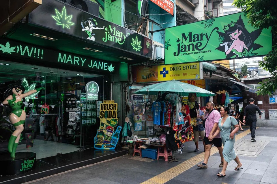 Orang ramai berjalan melepasi premis penjualan ganja Mary Jane di Bangkok pada 23 Mei 2025.