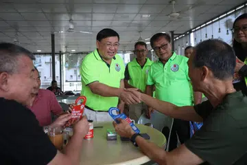 Pengerusi Parti Perikatan Demokratik Singapura (SDA), Encik Desmond Lim (tengah), serta anggota lain bermesra dengan penduduk di medan selera Loyang Point semasa lawatan pada 23 Mac.