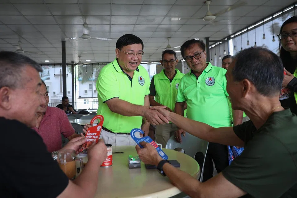 Pengerusi Parti Perikatan Demokratik Singapura (SDA), Encik Desmond Lim (tengah), serta anggota lain bermesra dengan penduduk di medan selera Loyang Point semasa lawatan pada 23 Mac.