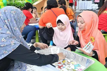 BERMAIN SAMBIL BELAJAR: Cik Puteri (kanan) bersama anaknya, Qisya, mencuba salah satu permainan pembelajaran di acara PlayFest 2019 anjuran Mendaki di Yishun Town Square semalam. - Foto MENDAKI