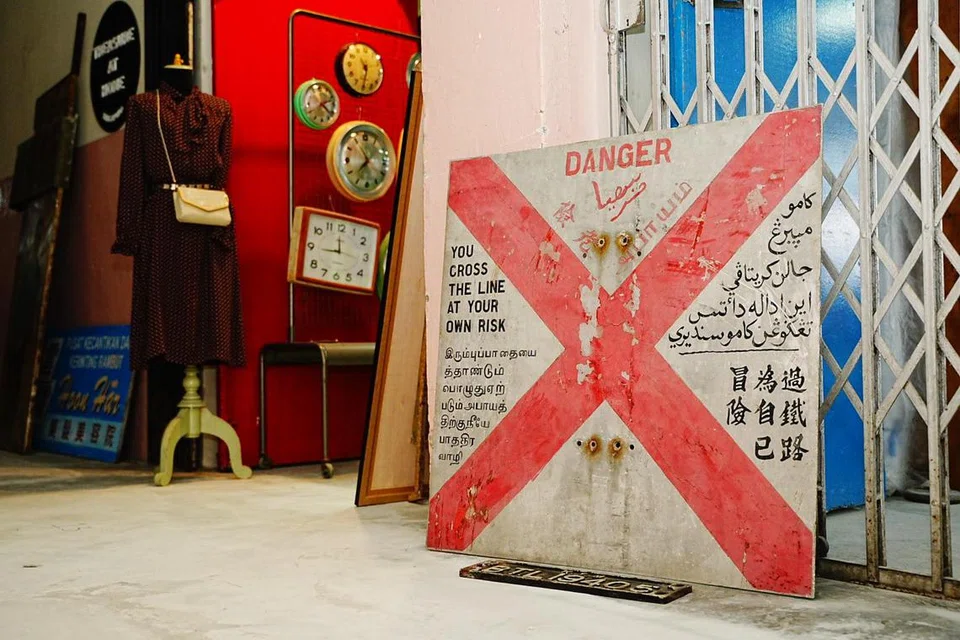 Sebuah papan tanda amaran lama yang ditulis dalam pelbagai bahasa, termasuk Tamil, Jawi dan Cina. Artifak itu dipercayai berasal dari era 1940-an dan merupakan sebahagian daripada Stesen Kereta Api Tanjong Pagar. 