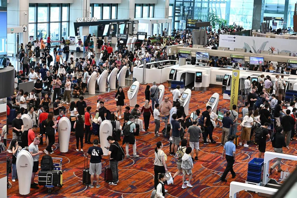Jumlah besar penumpang kelihatan sedang beratur di kaunter daftar masuk Scoot di Lapangan Terbang Changi Terminal 1 disebabkan gangguan sistem IT sedunia pada 19 Julai 2024.