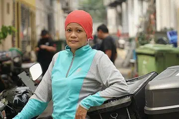 PENGHANTARAN ISTIMEWA 'HEROES TO HEROES': Cik Noryatti mengambil makanan buka puasa dari gerai Muhammad Shazain Faiha Muslim Food Paradise di Pasar Tiong Bahru untuk dihantar kepada pekerja migran di dormitori. Beliau antara 30 penghantar makanan Deliveroo yang terlibat dalam satu inisiatif kempen 'Heroes to Heroes' Deliveroo. - Foto DELIVEROO SINGAPURA