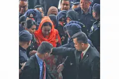 TEPI, BERI LALUAN: Datin Seri Rosmah (berbaju warna jingga) tiba di mahkamah pagi semalam di mana beliau dikenakan 12 pertuduhan pengubahan wang haram berjumlah lebih RM7 juta ($2.3 juta) selain pertuduhan gagal mengemukakan penyata pendapatan kepada Lembaga Hasil Dalam Negeri. - Foto AFP